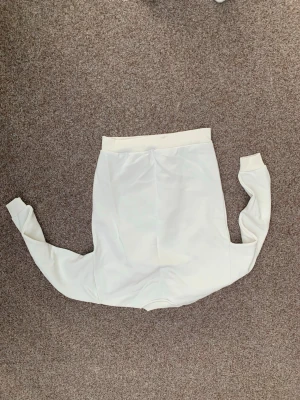 Vit sweatshirt från SMOG - Klassisk vit sweatshirt från SMOG i storlek XS. Tröjan har en relaxed fit och är tillverkad i mjukt bomullsmaterial. Ribbstickade muddar vid ärmslut och nederkant ger en clean look. Perfekt för en enkel och stilren outfit.