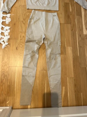 Beige sömlösa träningstights - Säljer ett par beige sömlösa träningstights med hög midja och tight passform. Materialet är stretchigt och mjukt, perfekt för gymmet eller yoga. Diskret mönster i tyget för en snygg look.