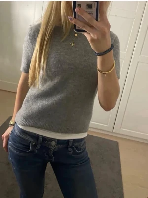 Grå stickad kortärmad topp - Mysig grå stickad topp med korta ärmar och rund hals. Perfekt till jeans eller kjol för en enkel och stilren look. Ribbad kant nedtill och vid ärmslut. Enkel att matcha och superbekväm.💕