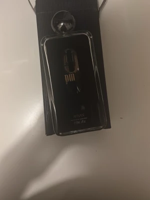 Afnan 9PM Eau de Parfum 100ml - Afnan 9PM Eau de Parfum är en elegant parfym i en svart och transparent glasflaska med silverfärgad rund kork. Flaskan har en modern design med tydlig logga och stilren etikett. Innehåller 60 ml doft som passar dig som gillar exklusiva och djärva parfymer.