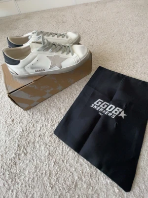 Vita golden goose sneakers. - Snygga vita sneakers från Golden Goose med grå stjärna på sidan och grå detaljer. Med skorna kommer med originalkartong och dust bag. Den är helt ny och passar perfekt inför sommar.
