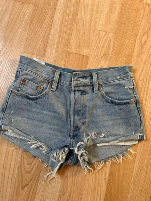 Levi's blå jeansshorts med fransar - Säljer ett par klassiska blå jeansshorts från Levi's med hög midja, inte använt på ett par år pågrund av passar inte mig längre. Storlek w25