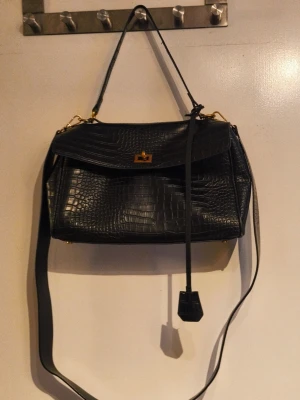 🖤 Black Croc-Embossed Shoulder & Crossbody Bag ✨ - Elegant, timeless and surprisingly spacious. 🖤 This beautiful black bag features a croc-embossed finish with gold-tone hardware, giving it a sophisticated look that works just as well for everyday outfits as for dinners or evenings out.  The structured silhouette is complemented by a practical interior with multiple compartments, making it easy to keep your essentials organised. Carry it by the shorter shoulder strap or attach the longer strap for comfortable crossbody wear.✨