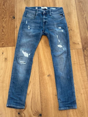 Replay jeans ANBASS - Säljer ett par blå jeans från replay med slim fit och slitna detaljer framtill. Perfekta för en avslappnad och trendig look. (29/32 storlek)