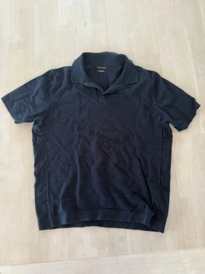 Blå pikétröja - Klassisk  pikétröja från med krage och korta ärmar. Tröjan har en enkel knappslå framtill och är tillverkad i mjuk bomull som känns skön mot huden. Perfekt till jeans eller shorts för en clean look.