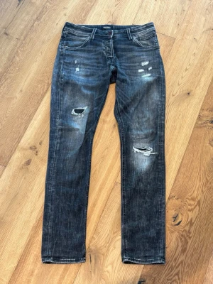 Jack & Jones jeans LIMITED EDITION  - Säljer ett par svarta jeans med slitningar och hål på både lår och knä. Snyggt tvättade detaljer och råa kanter ger en cool och avslappnad look. (31/34 storlek)