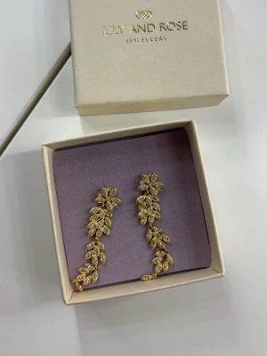 Guldiga örhängen från Lily and Rose - Säljer ett par guldiga örhängen som jag fick i studentpresent. Dom är helt oanvända men är lite osäker på vart dom kommer ifrån. Kan vara så att dom är köpta från Hallbergs guld men kommer från märket Lily and Rose. Perfekta för dig som vill sticka ut med snygga accessoarer.