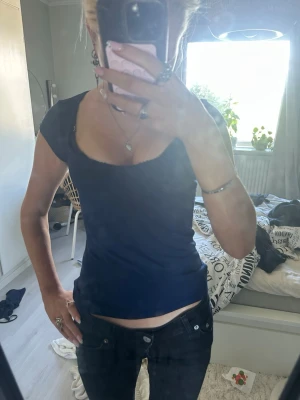 Mörkblå topp med spetskant Nelly - Snygg mörkblå topp från Nelly i storlek XS. Modellen har korta ärmar, djup urringning och en söt spetskant längs halsringningen. Perfekt att matcha med jeans eller kjol för en trendig look.