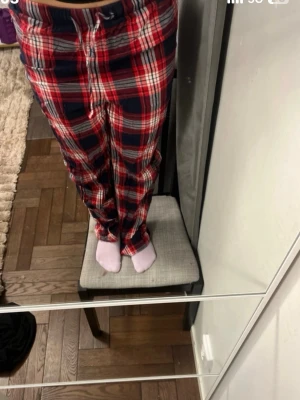 Rödblåa rutiga pyjamasbyxor - Säljer ett par mysiga pyjamasbyxor med rött, blått och vitt rutmönster. Byxorna har dragsko i midjan och raka ben, perfekta för chillkvällar hemma. Mjukt material som känns skönt mot huden.