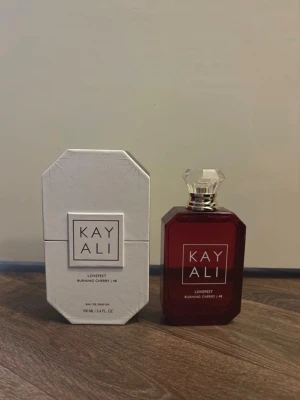Kayali Lovefest Burning Cherry  - Kayali Lovefest Burning Cherry 48 Eau de Parfum i en elegant mörkröd, multifacetterad glasflaska med genomskinlig kristallkork. Kommer med en vit, geometrisk förpackning. Doften är känd för sina söta och fruktiga körsbärstoner. Endast testad, 100ml.