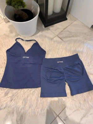Steel DFYNE - Säljer ett blått träningsset från DFYNE med ett linne med smala axelband och matchande shorts. Setet är gjort i ett stretchigt funktionsmaterial som passar perfekt för gym eller yoga. Båda plaggen har DFYNE-loggan tryckt framtill. Impact i färgen steel 4.5. Priset är lägre på denna pga av sista bilden 