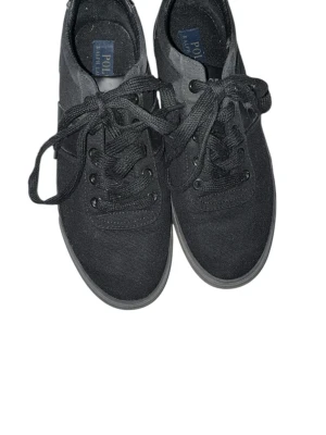 Svarta sneakers från Polo Ralph Lauren - Stilrena svarta sneakers från Polo Ralph Lauren med klassisk logga på sidan. Skorna har snörning och är tillverkade i textil med detaljer i skinn. Perfekta för en clean och enkel look.