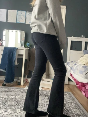 Svarta bootcut jeans - Säljer ett par svarta bootcut jeans med hög midja och utsvängda ben. Jeansen har klassisk femficksdesign och är i stretchigt material som sitter snyggt. Perfekta till sneakers eller boots för en trendig look.