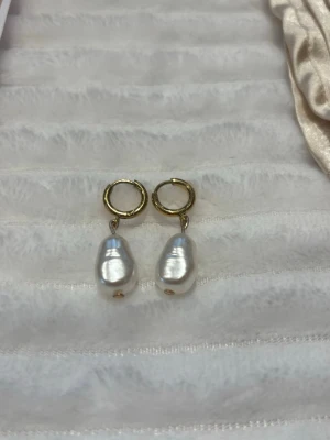 Guldörhängen med vita barockpärlor🌟 - Säljer ett par snygga örhängen med guldfärgade ringar och droppformade vita barockpärlor. Örhängena har en modern och stilren look som passar perfekt till olika outfits. Materialet är rostfritt stål🌸 Alla örhängen på sista bilden finns att köpa i både guld och silver