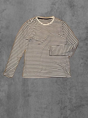 Randig långärmad t-shirt - Klassisk långärmad t-shirt  med marinblå och vita ränder. Tillverkad i mjuk bomull och har en rund halsringning. Perfekt för en avslappnad och stilren look.