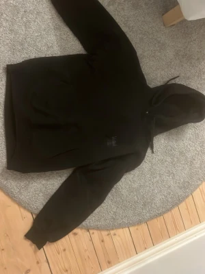 Svart hoodie från Vailent - Säljer en svart hoodie från Vailent i storlek S. Hoodien har klassisk huva med snören och en stor magficka framtill. Materialet är mjukt och bekvämt, perfekt för chill dagar. Enkel design med diskret logga på bröstet.