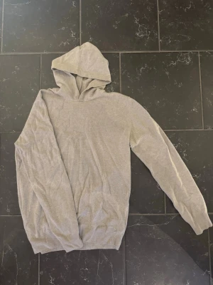 Ljusgrå hoodie i mjukt material - En enkel och stilren ljusgrå hoodie med huva och långa ärmar. Tillverkad i ett mjukt, tunt tyg som känns skönt mot huden. Perfekt för dig som gillar en clean och avslappnad look. Inga synliga loggor eller tryck.