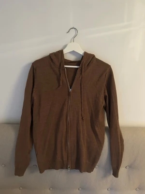 Stenströms merinoull hoodie  - Snygg brun hoodie med dragkedja framtill och justerbara snören i huvan. Tillverkad i ett mjukt och tunt material som känns skönt mot huden. Perfekt för dig som gillar en enkel och stilren look. Långa ärmar och ribbade muddar vid ärmslut och nederkant. 100% merinoulls hoodie. Kontakta vid eventuella frågor!😁