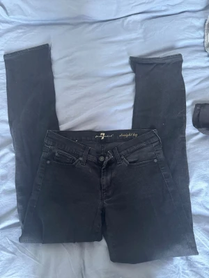 Svarta straight leg jeans 7 For All Mankind - Säljer ett par svarta straight leg jeans från 7 For All Mankind. Klassisk femficksmodell med normal midja och diskret logga på bakfickan. Jeansen har en stilren look och passar perfekt till alla typer av outfits.