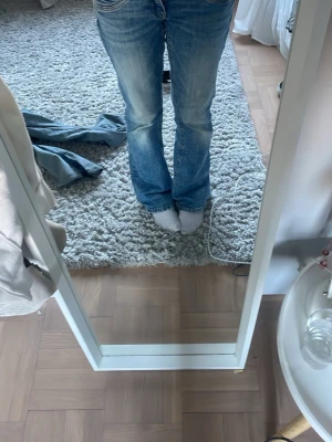 Blå bootcut jeans med slitningar - Säljer ett par blå jeans med bootcut-modell och snygga slitningar. Jeansen har klassisk femficksdesign, låg midja och är tillverkade i denim. Perfekta för dig som gillar en avslappnad och trendig look. Andvänd ganska mycket men ganska bra skick. Det står ingen lapp men skulle gissa på 164 🤗