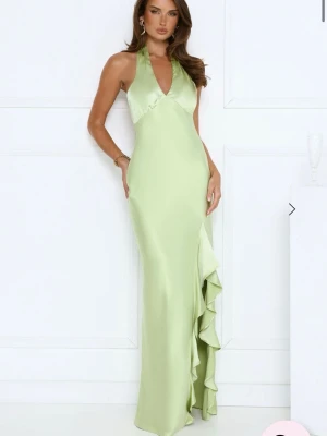 Ljusgrön balklänning i satin - Elegant ljusgrön långklänning i satin med halterneck, öppen rygg och v-ringad urringning. Klänningen har en slits längs sidan och knyt i nacken för en snygg siluett. Perfekt för bal eller andra tillställningar🫶💚Endast testad med prislapp kvar, nypris 1250 kr