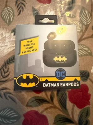 Batman trådlösa earpods DC - Snygga svarta trådlösa earpods med Batman-logga på både hörlurar och laddningsetui. Perfekt för dig som gillar superhjältar och vill ha cool design på dina hörlurar. Kommer i originalförpackning med laddningsetui.