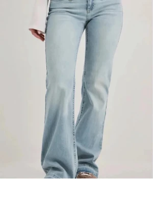 Ljusblå bootcut jeans - Säljer ett par ljusblå bootcut jeans med klassisk femficksmodell och hög midja. Jeansen har en snygg tvättad look och är tillverkade i mjukt denimtyg med lite stretch för extra komfort. Perfekta för en avslappnad och trendig stil. Helt oanvända fel storlek! Så hör av er om någon vill byta mot ett par 34! 