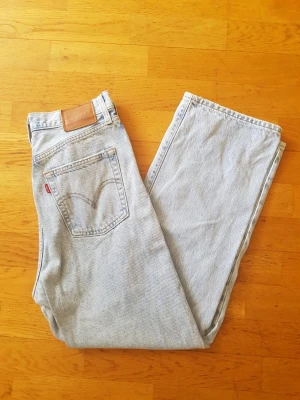 Ljusblå Levi's raka jeans - Säljer ett par klassiska ljusblå Levi's jeans i rak modell. Jeansen har fem fickor, Levi's ikoniska röda etikett på bakfickan och patch i läder bak i midjan. Tillverkade i slitstark denim, perfekta för en avslappnad och tidlös stil.