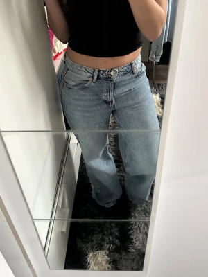 Ljusblå raka jeans med hög midja - Säljer ett par ljusblå jeans med rak passform och hög midja. Jeansen har klassisk femficksdesign och stängs med dragkedja och knapp. Perfekta för en avslappnad och trendig look.