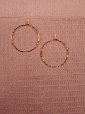 Tunna guldfärgade hoops örhängen - Säljer ett par tunna,hoops i guldfärg. De är runda och minimalistiska, perfekta för dig som gillar enkel men snygg stil. Inget märke syns på örhängena och materialet ser ut att vara metall.
