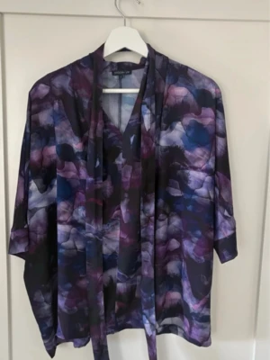 Mönstrad blus med knytband - Säljer en luftig blus från Stockh LM med abstrakt mönster i lila, blått och svart. Blusen har trekvarts, fjärildarm och ett snyggt knytband för midjan. Materialet känns lätt och flowy och blusen gör sig mycket finare i verkligheten än på bild. Den ena bandhållaren gick sönder. Se bild på hur den andra ser ut. Kan man säkert fixa själv 😊
