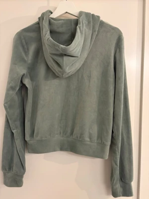 Grön velourhoodie med dragkedja - Mjuk grön hoodie i velour från Gina Tricot med dragkedja framtill, huva med dragsko och två stora fickor. Perfekt för en chill och avslappnad stil. Långa ärmar och ribbade muddar ger en skön passform.