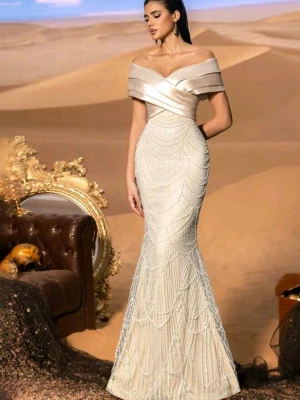 Elegant offshoulder långklänning - Supersnygg långklänning i ljus champagnefärg med offshoulder-detalj och figurnära passform. Klänningen har ett vackert mönster av pärlliknande broderier och en lätt glansig finish upptill. Perfekt för bal eller festliga tillfällen. Haft på mig den en gång och köpt för 1000kr. För bilder med klänningen är det bara att skriva så skickar jag!💕