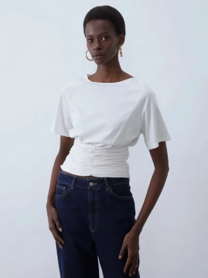 Vit topp med rynkdetalj Anna Field - Snygg vit topp från Anna Field med korta ärmar och rynkdetalj i midjan som ger en smickrande passform. T-shirten har en rund halsringning och är tillverkad i mjukt material som känns skönt mot huden. Perfekt att styla med jeans eller kjol.