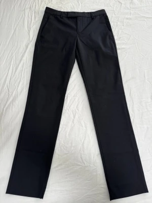 Svarta raka kostymbyxor - Snygga svarta kostymbyxor med rak passform och klassisk design. Byxorna har hällor för bälte, sidfickor fram och en bakficka.