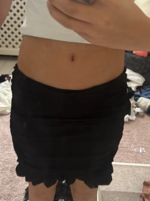 Svart volangkjol i kort modell - Snygg svart kortkjol med volangkant nertill. Kjolen har en tight passform