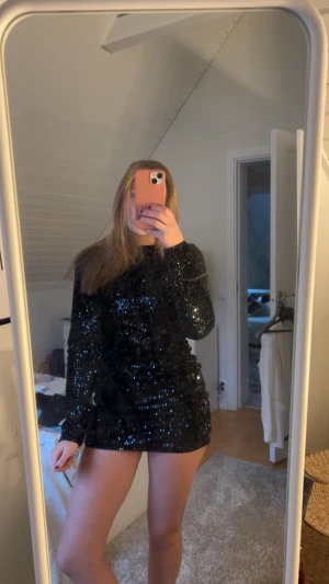 Svart glittrig paljettklänning - Supersnygg svart kort klänning med massor av paljetter som glittrar. Långärmad modell med öppen rygg och knyt i nacken. Tight passform som framhäver figuren. Den är bara använd två gånger