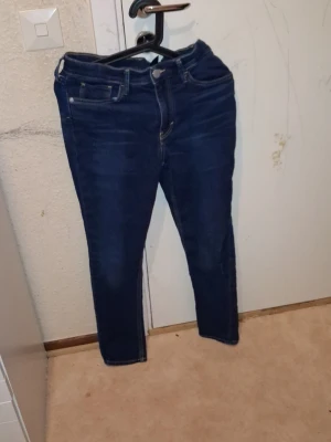 Mörkblå skinny jeans (Man) - Säljer ett par mörkblå skinny jeans med klassisk femficksdesign och dragkedja framtill. Jeansen har smal passform och är tillverkade i stretchigt denim-material som sitter snyggt och bekvämt. Perfekta för dig som gillar en stilren look.
