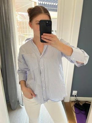 Blårandig skjorta med knappar - Säljer en klassisk blårandig skjorta med vit bas och tunna blå ränder. 