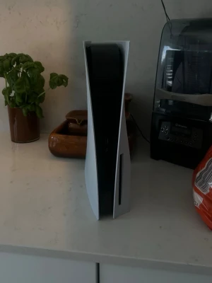PlayStation 5 spelkonsol vit - PlayStation 5 från Sony med futuristisk design i vit och svart plast. Konsolen har en slimmad, stående form och är utrustad med diskdrive för fysiska spel. Perfekt för gaming med kraftfull prestanda och stöd för nya spelupplevelser.