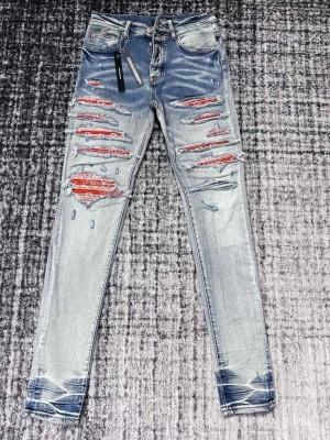 Ljusblå slitna skinny jeans - Säljer ett par ljusblå skinny jeans med kraftiga slitningar och röda detaljer under de trasiga partierna. Jeansen har fem fickor, dragkedjegylf och en cool tvätt med slitna effekter vid benslut och lår. Perfekta för en edgy streetstyle-look.