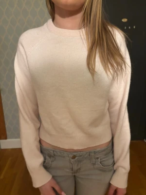 Ljusrosa stickad tröja - Mysig ljusrosa stickad tröja med rund halsringning och långa ärmar. Tröjan har en enkel och stilren design med ribbstickade muddar vid ärmslut och nederkant. Perfekt för lager-på-lager och passar till det mesta.