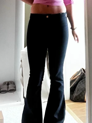 Svarta bootcut jeans med hög midja - Snygga svarta bootcut jeans med hög midja och klassisk femficksdesign. Jeansen har en figurnära passform upptill och utsvängda ben. Perfekta till crop tops eller oversized tröjor för en trendig look.