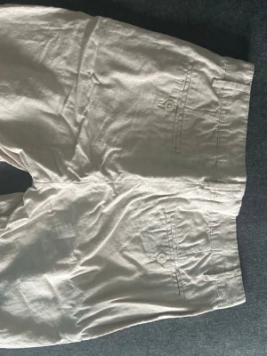 Linne short helt nyt - Säljer ett par superhärliga shorts i linne som tyvärr aldrig kommit till användning. De är i absolut nyskick, helt oanvända och redo för soliga dagar. Materialet är lätt och svalt, vilket gör dem otroligt sköna att bära när det är varmt ute. Färgen är en klassisk ljus nyans som är enkel att matcha med både en enkel t-shirt eller en snyggare skjorta. 