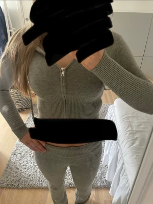 Mjukis set - Mysigt stickat loungewear-set i grönt med långärmad ziptröja och matchande byxor. Tröjan har ribbade muddar och byxorna har en dekorativ spänndetalj i midjan. Köpt second hand och hittar ingen lapp men det sitter som xxs. 