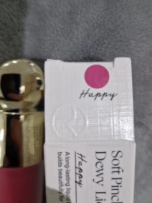 Rare Beauty Soft Pinch Dewy Liquid Blush - Flytande rouge från Rare Beauty i nyansen Happy, en fräsch och livlig rosa färg. Kommer i en stilren frostad glasflaska med guldig kork. Ger en daggig finish och är lätt att applicera för ett naturligt glow.