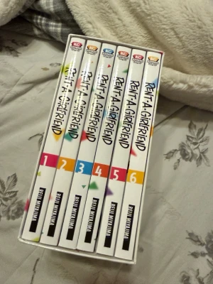 Rent-A-Girlfriend Manga Box Set 1-6 + 2st dubbelsidiga posters - Säljer en box med manga-serien Rent-A-Girlfriend, volym 1 till 6, skapad av Reiji Miyajima. Böckerna har färgglada omslag med anime-inspirerade illustrationer och är på engelska. Perfekt för dig som gillar romantisk komedi och manga.