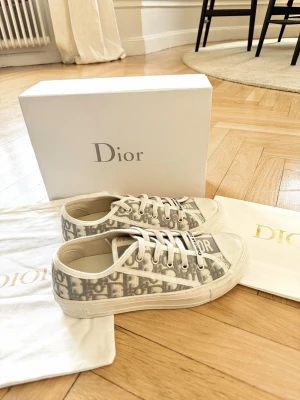 Dior sneakers / Walk N Dior  - Säljer mina gråa / vita dior skor som är i storlek 38! Låda dustbag & inslagningspapper finns med. Skorna är i väldigt bra skick, lite smutsiga men inget som är fel med skorna❤️ Kan mötas upp i Stockholm!