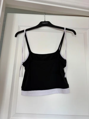 Linne med dubbla axelband - Linne med dubbla axelband, det vita är knytbart och det är även en vit kant längst ner så det ska se ut som det är dubbla linnen.