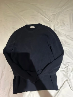 Mörkblå tröja These Glory Days - Snygg mörkblå tröja från These Glory Days i storlek S. Tröjan har rund halsringning, lång ärm och är tillverkad i ett mjukt, stickat material med diskret struktur. Perfekt för en stilren och enkel look.